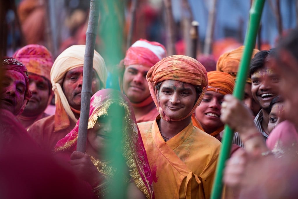 A man enjoys looking while women playfully beat lathis 