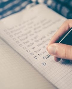 fotografia de uma pessoa fazendo seu checklist de viagem em seu caderninho