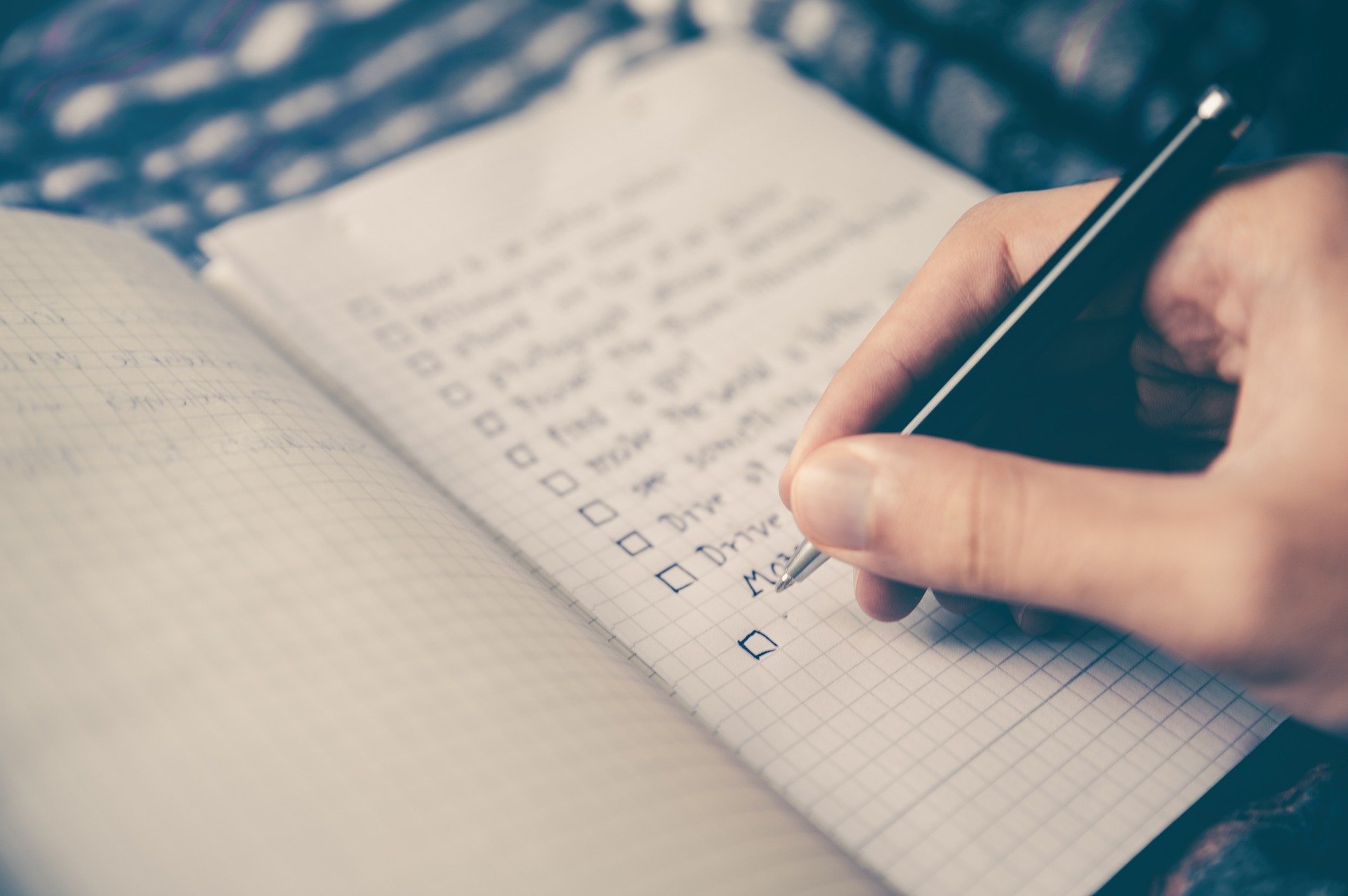 fotografia de uma pessoa fazendo seu checklist de viagem em seu caderninho